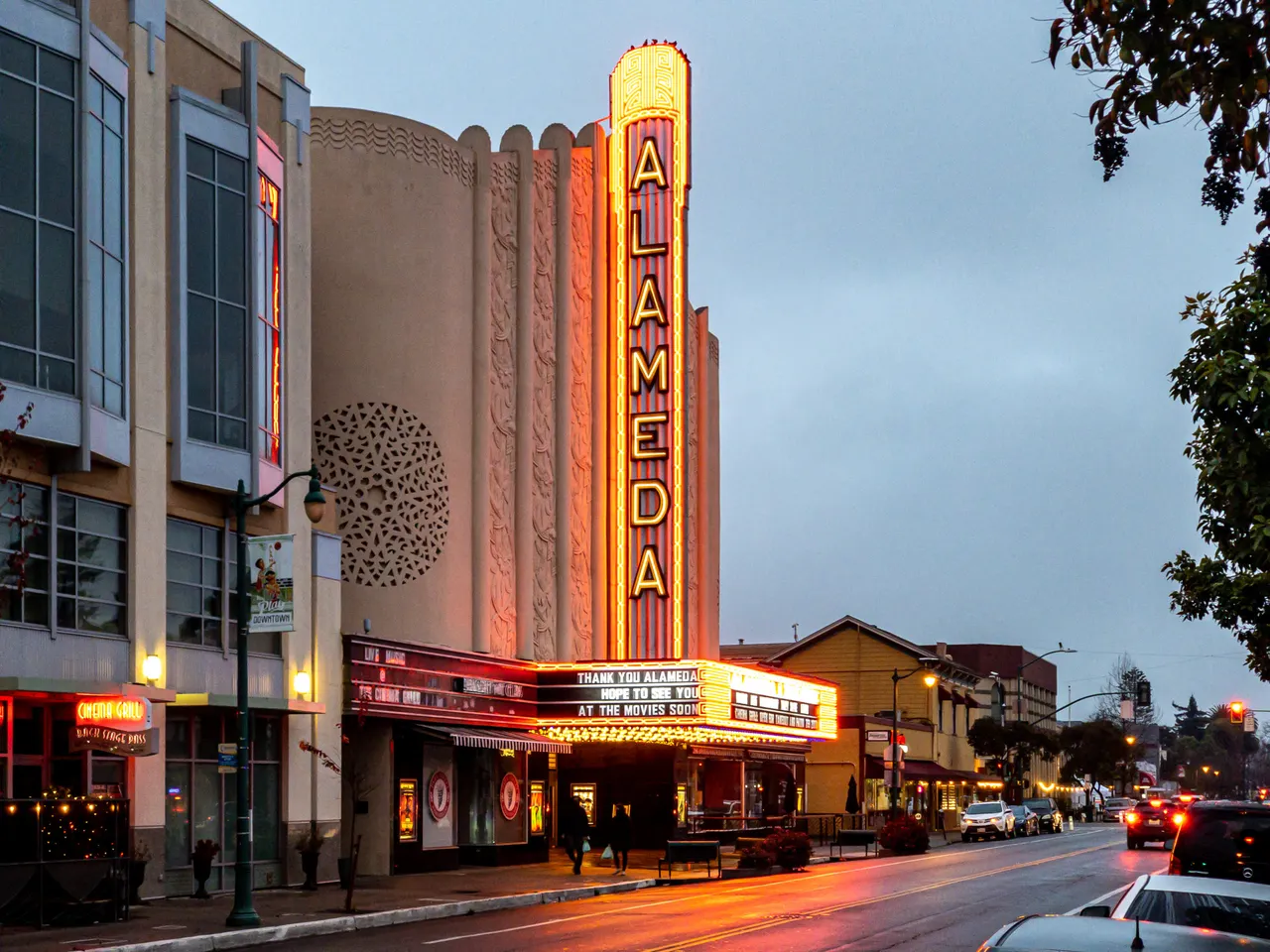 The illuminated Alameda Theatre marquee and neighboring buildings along Central Avenue in Alameda.