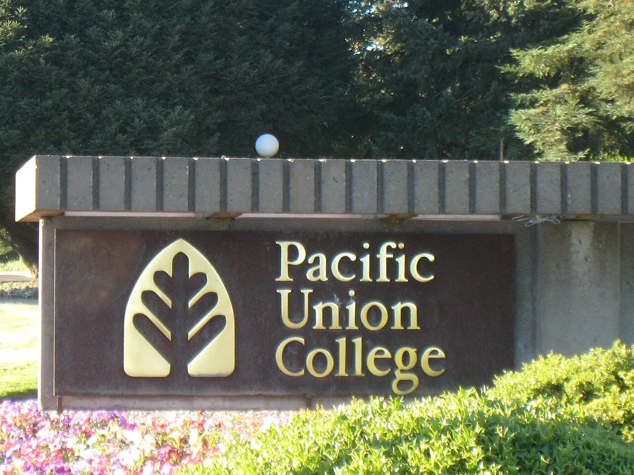 The Pacific Union College entrance sign among trees and flowers in Angwin.