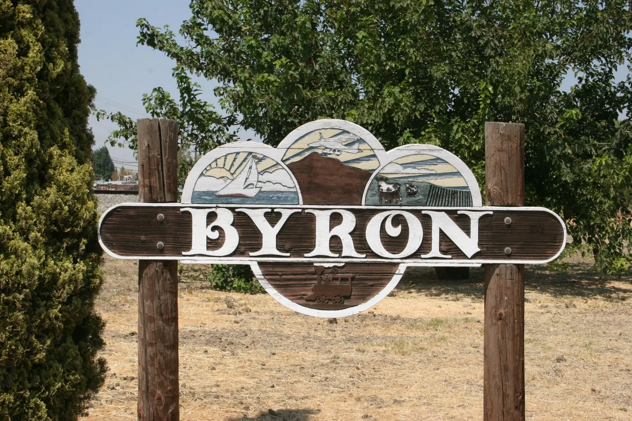 The decorative Byron community sign framed by trees.