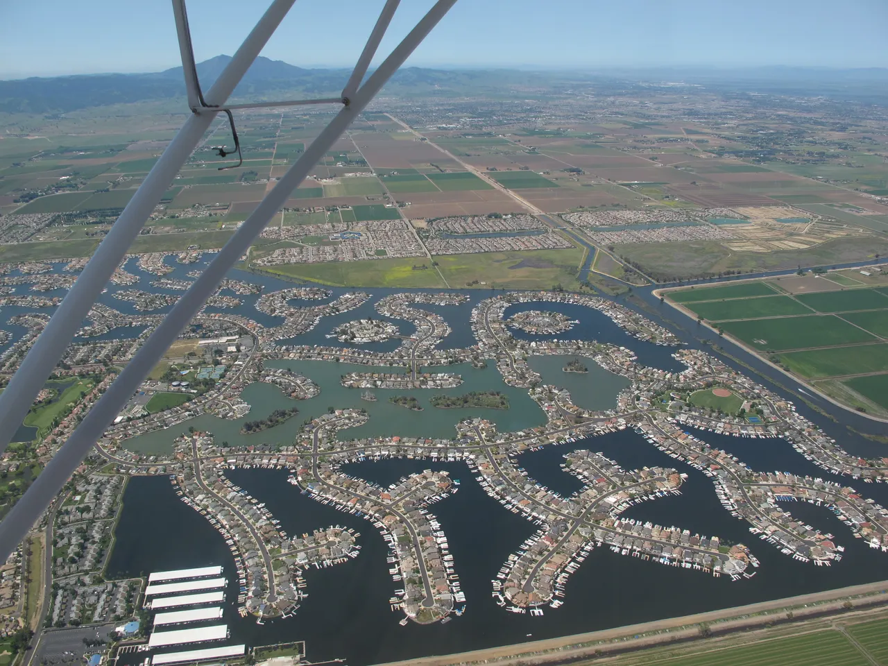 An aerial view of Discovery Bay homes, waterways and marina, seen past airplane struts.