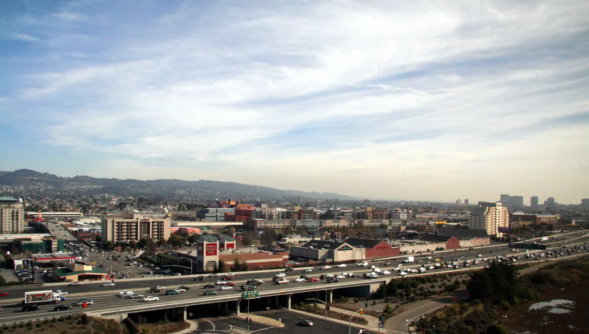 Emeryville buildings and freeway approaches seen from the marina area, with hills in the distance.