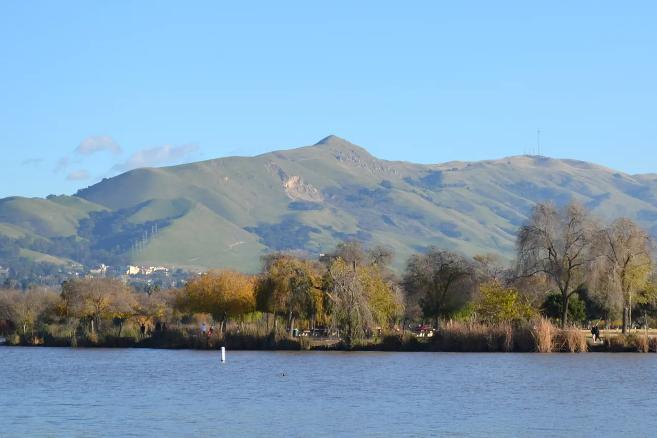 Mission Peak above Lake Elizabeth in Fremont, with trees lining the shore.