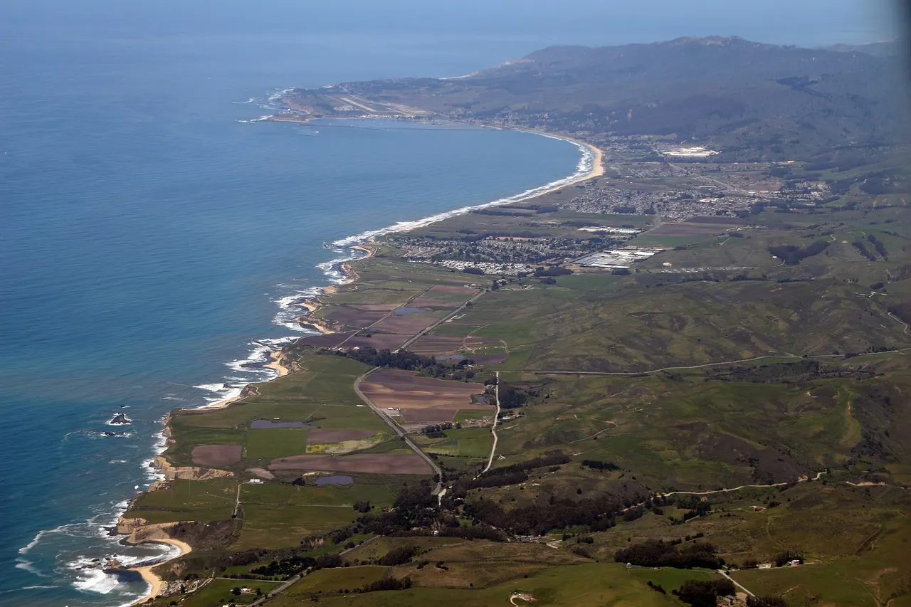 Aerial view along the Half Moon Bay coast, with Pillar Point Harbor in the distance.