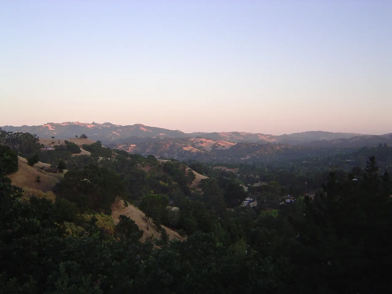 Wooded hills and residential ridgelines in Lafayette beneath a pale evening sky.