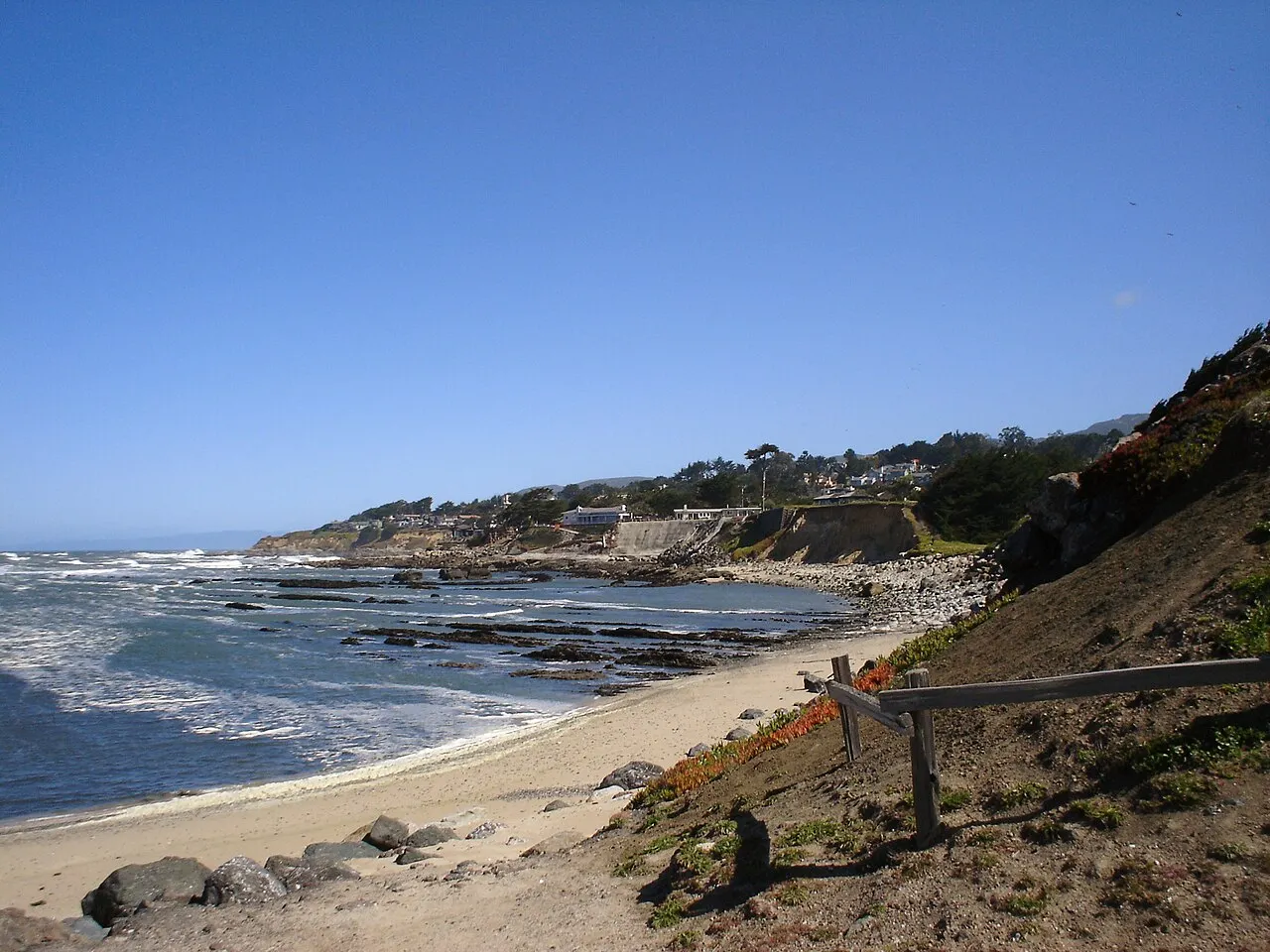 The Moss Beach shoreline below coastal homes on a clear day.