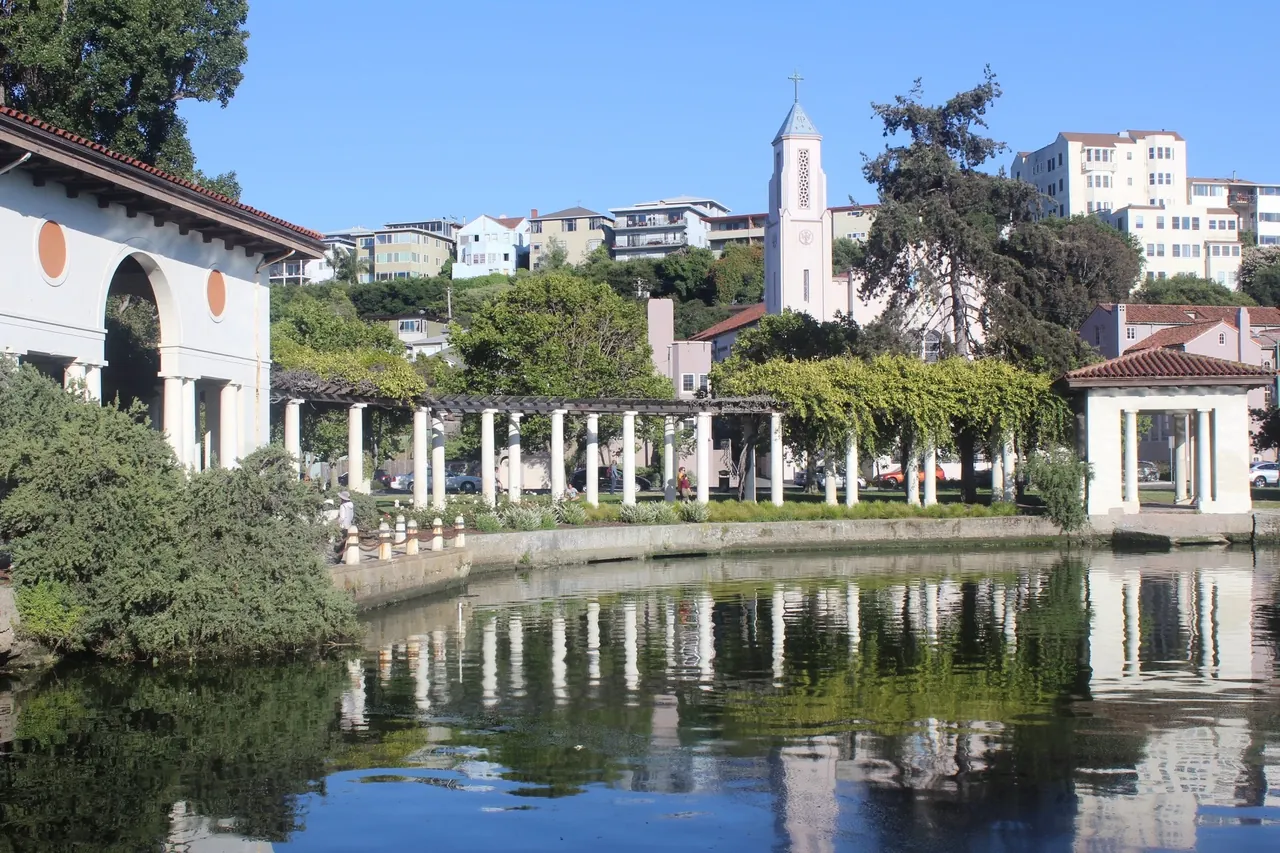 The white colonnade beside Lake Merritt in Oakland, reflected in the water below hillside buildings.