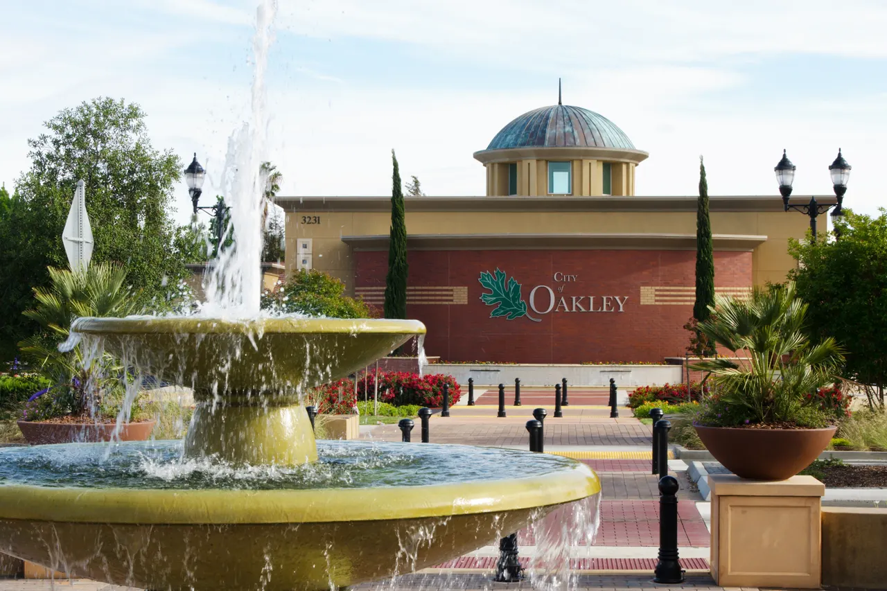 A fountain, landscaped plaza and Oakley City Hall.
