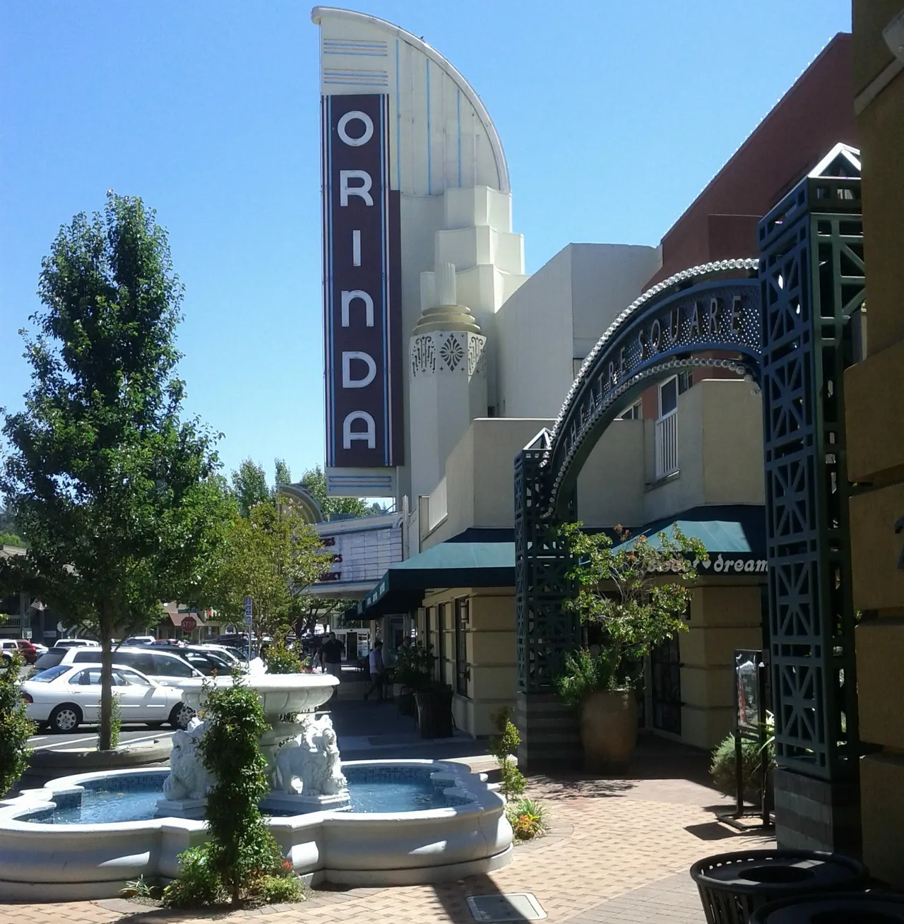 The vertical Orinda Theatre sign above storefronts on a sunny street.