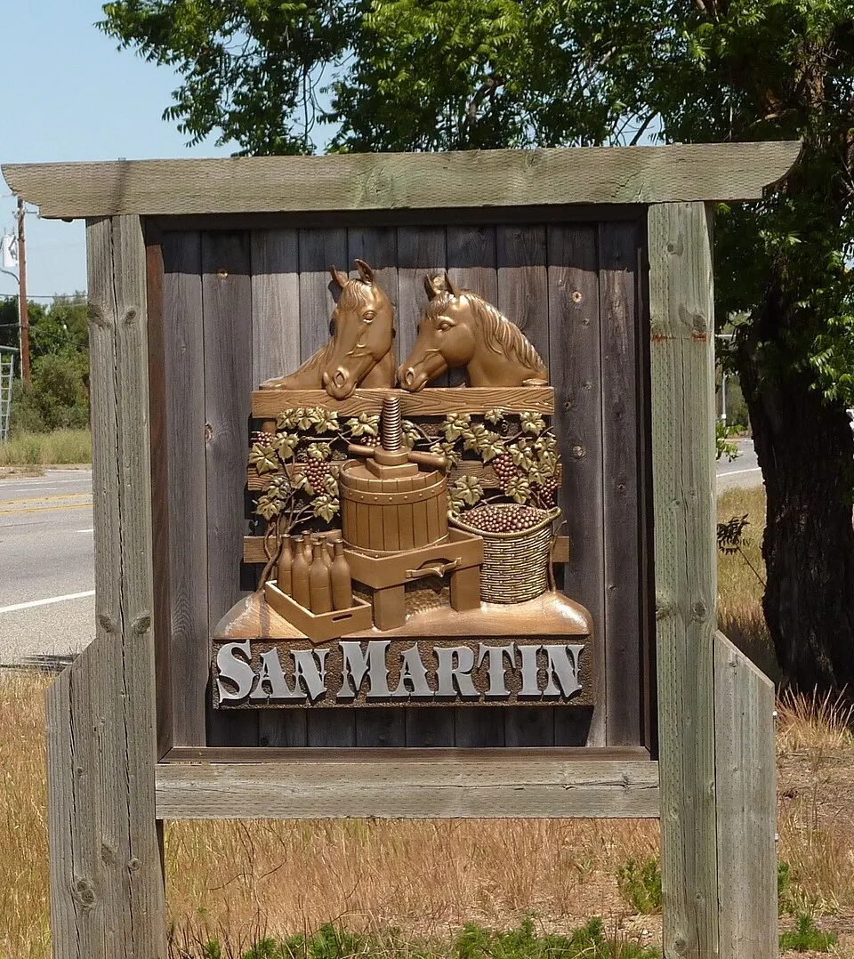 A carved wooden welcome sign beside Monterey Road in San Martin.